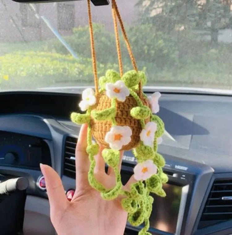 Green and white knitted wool car plant decoration with white hanging rope.