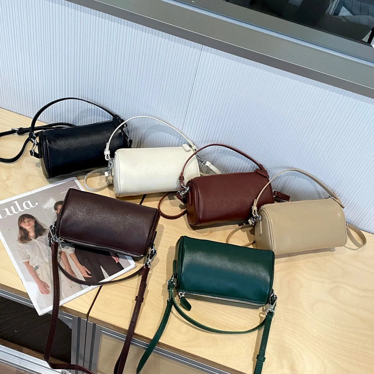 Soft vegetable-tanned leather crossbody phone bag in cylindrical shape with adjustable strap.