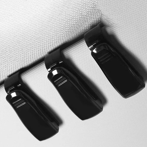 Black plastic clip for car sun visor holding a pair of glasses and a ticket.