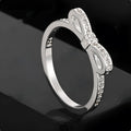 Silver-coloured bow-shaped ring with rhinestone and zircon crystal decoration on a white background.