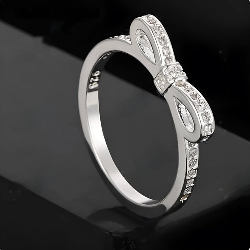 Silver-coloured bow-shaped ring with rhinestone and zircon crystal decoration on a white background.