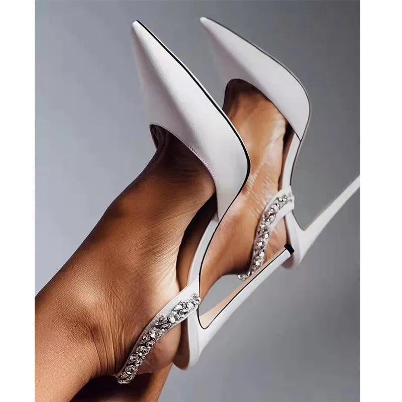 Women's black patent leather pointed toe stiletto sandals with rhinestone decorations along the side.