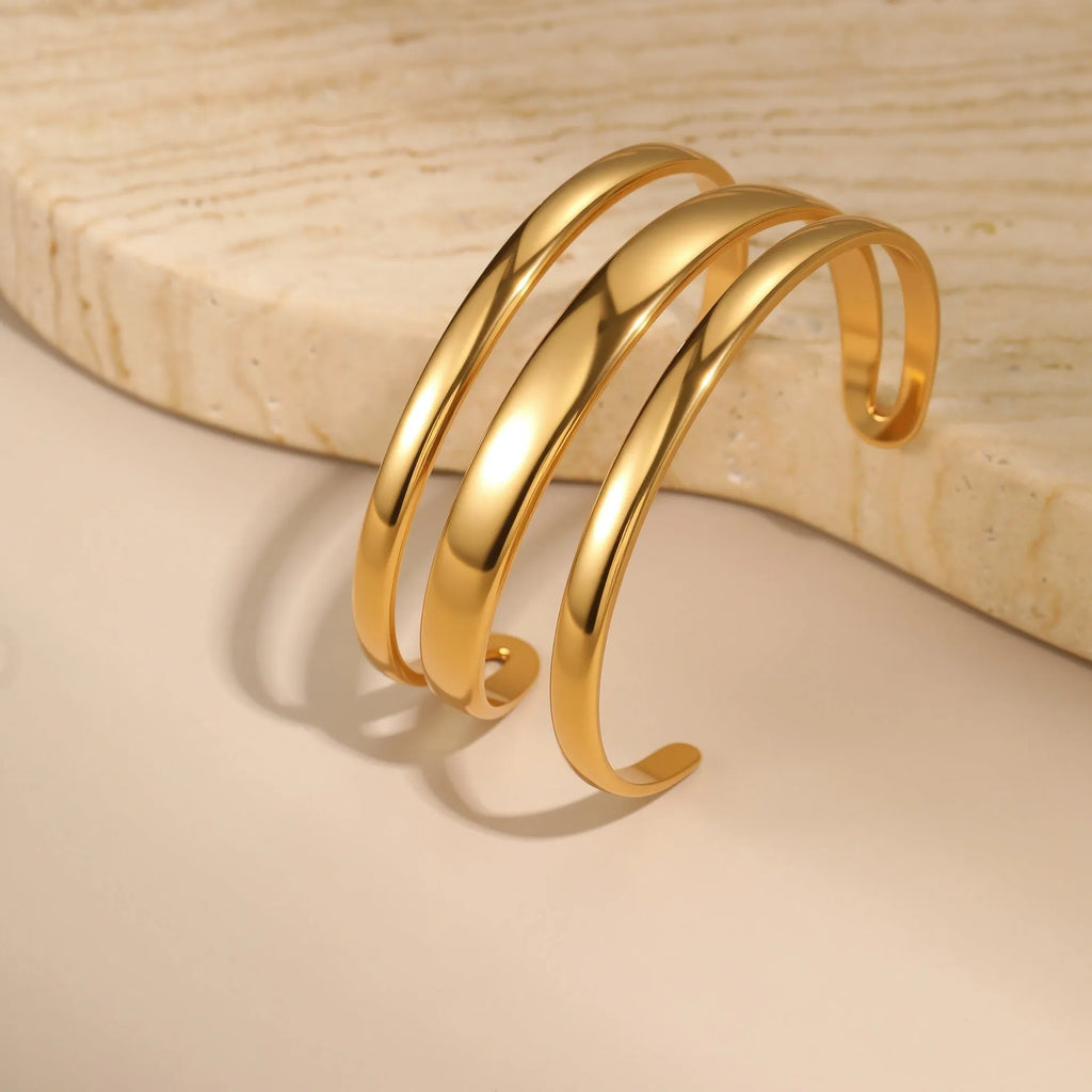 Geometric stainless steel women's bracelet with a simple opening mechanism, shown in gold and steel finish options.