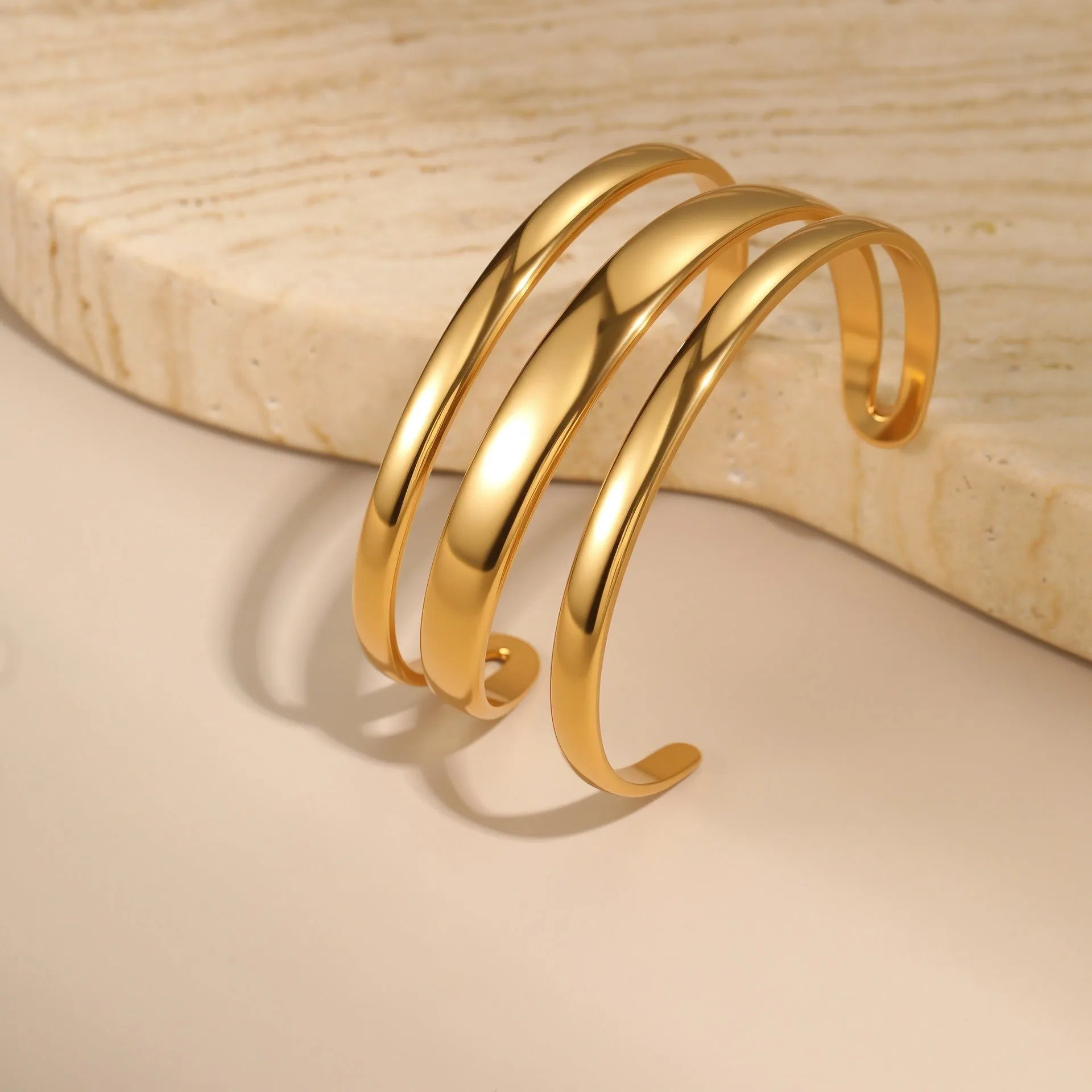 Geometric stainless steel women's bracelet with a simple opening mechanism, shown in gold and steel finish options.