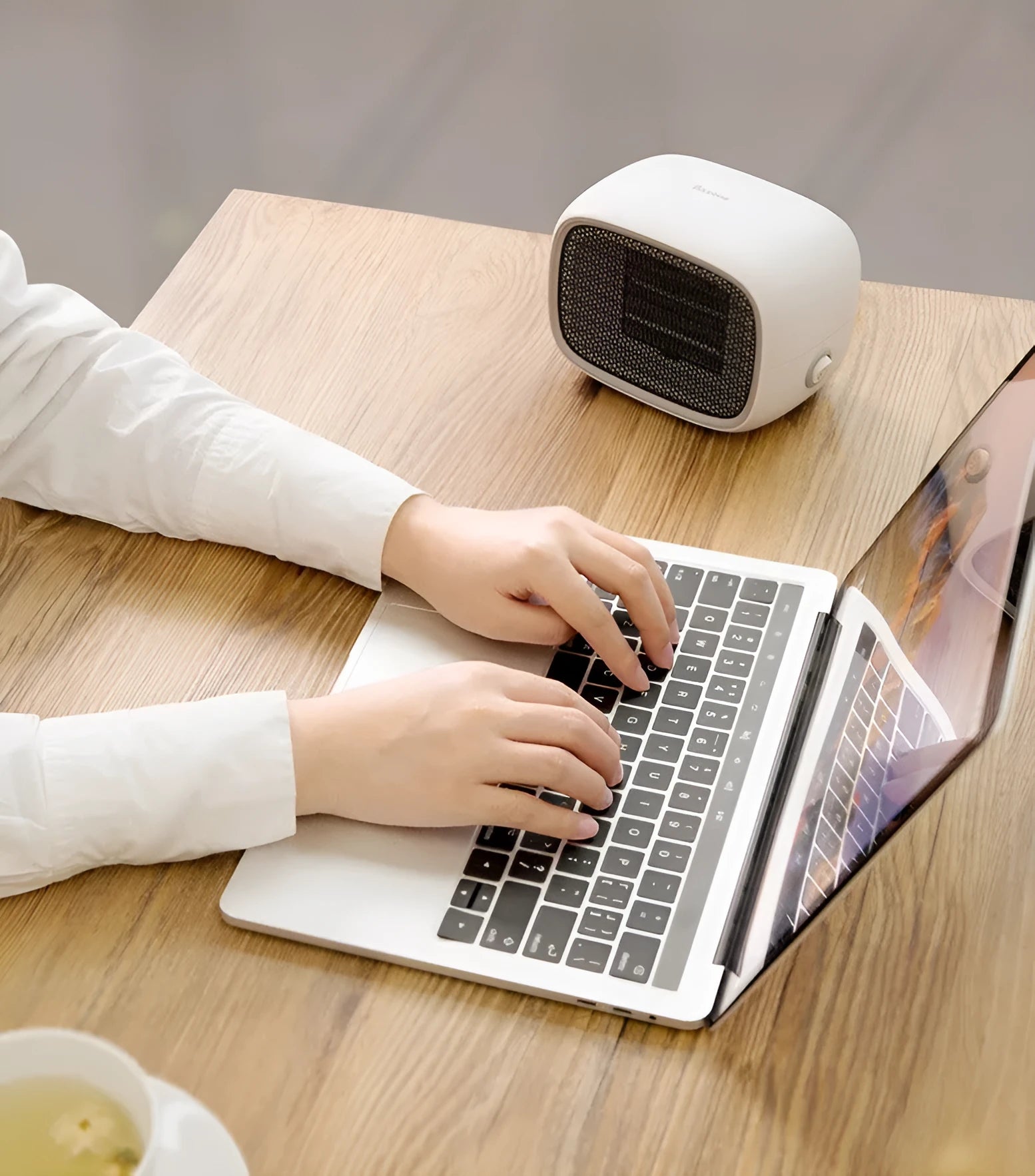 Compact green portable ceramic fan heater with metal grille, shown on a desk