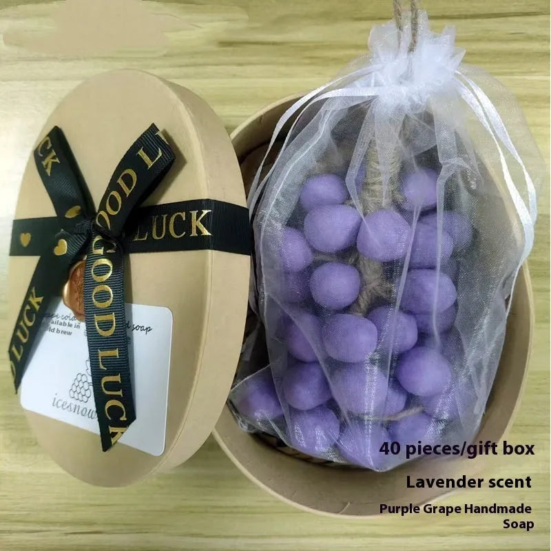 Handmade grape soap bars in black, green, and purple grape scents alongside litchi soap, with gift box and mesh bag packaging