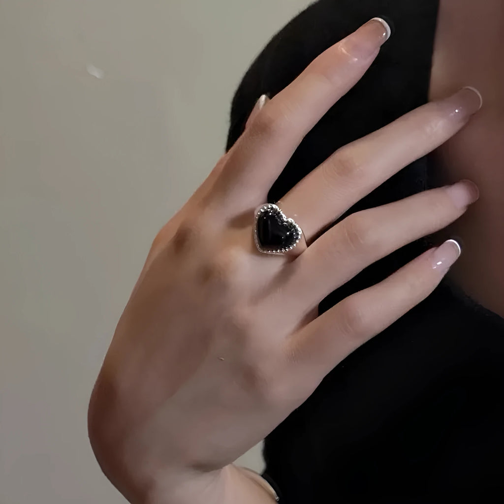 S925 sterling silver adjustable ring with a black agate heart centrepiece on a finger.