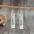 Silver geometric drop earrings with turquoise inlay details on white background