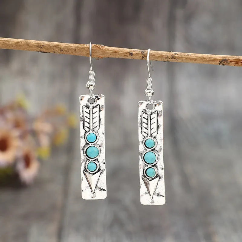 Silver geometric drop earrings with turquoise inlay details on white background