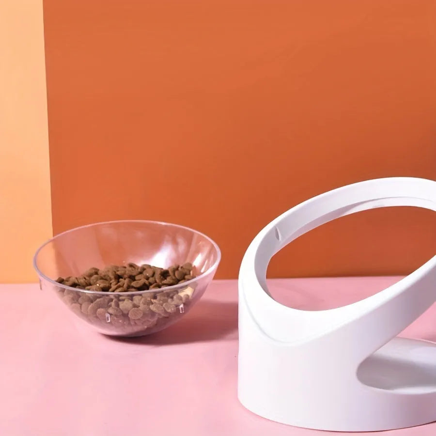 Clear plastic tilted cat food bowl on a flat surface