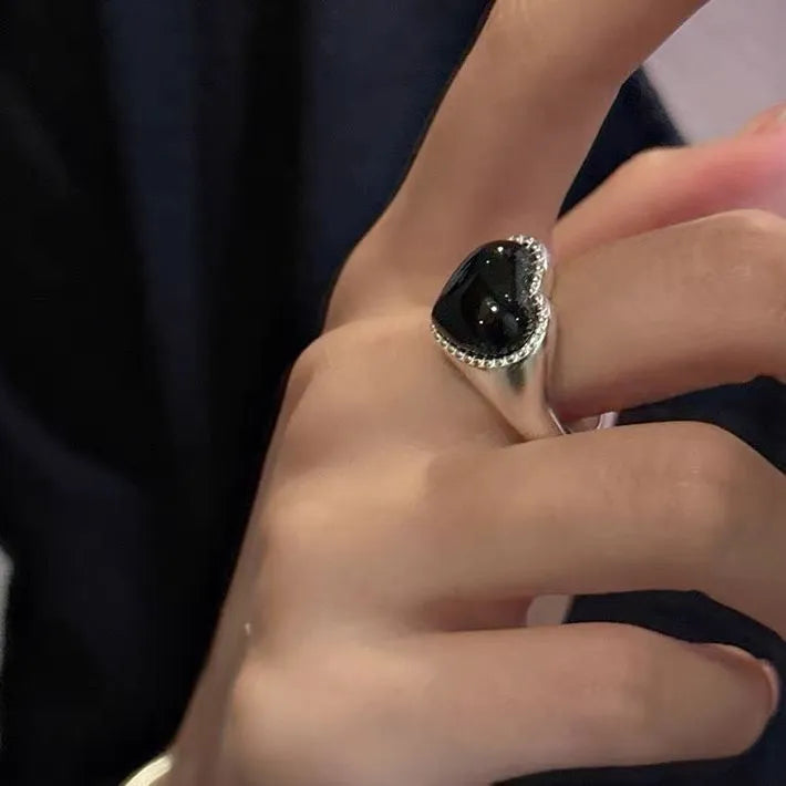 S925 sterling silver adjustable ring with a black agate heart centrepiece on a finger.