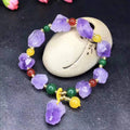 Women's amethyst bracelet with natural shaped beads and a fu character charm on an adjustable band.