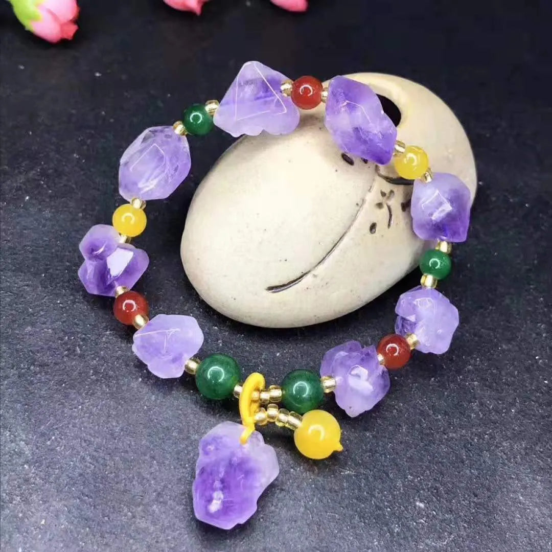 Women's amethyst bracelet with natural shaped beads and a fu character charm on an adjustable band.