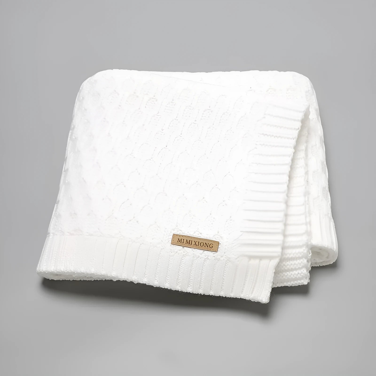 Solid colour infant hug blanket with three-dimensional line texture, shown in a choice of colours.