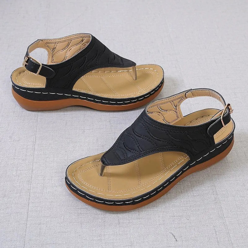 Women's black casual wedge heel flip flop sandals showing adjustable back buckle strap and solid colour design.