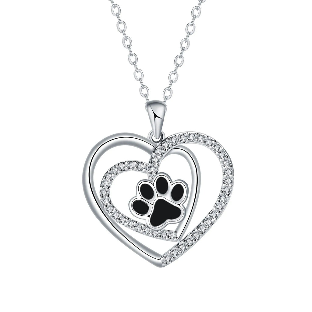 Close-up of a women's heart-shaped copper necklace with a detailed dog paw print pendant on a cross chain.