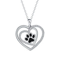 Close-up of a women's heart-shaped copper necklace with a detailed dog paw print pendant on a cross chain.