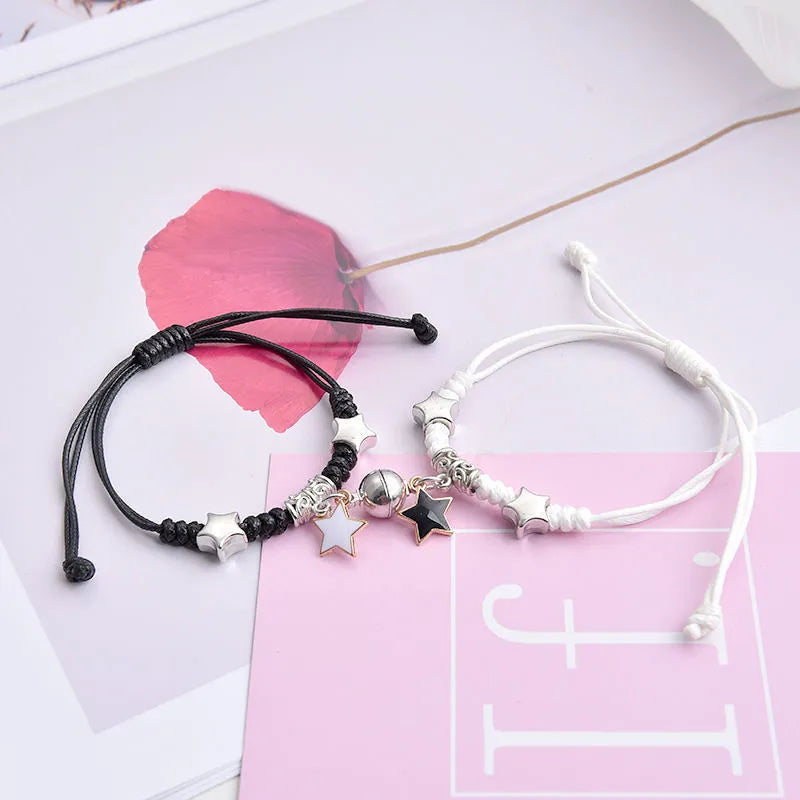 Pair of magnet couple bracelets with suction clasp on wrist, showing alloy designs like crown and love lock.