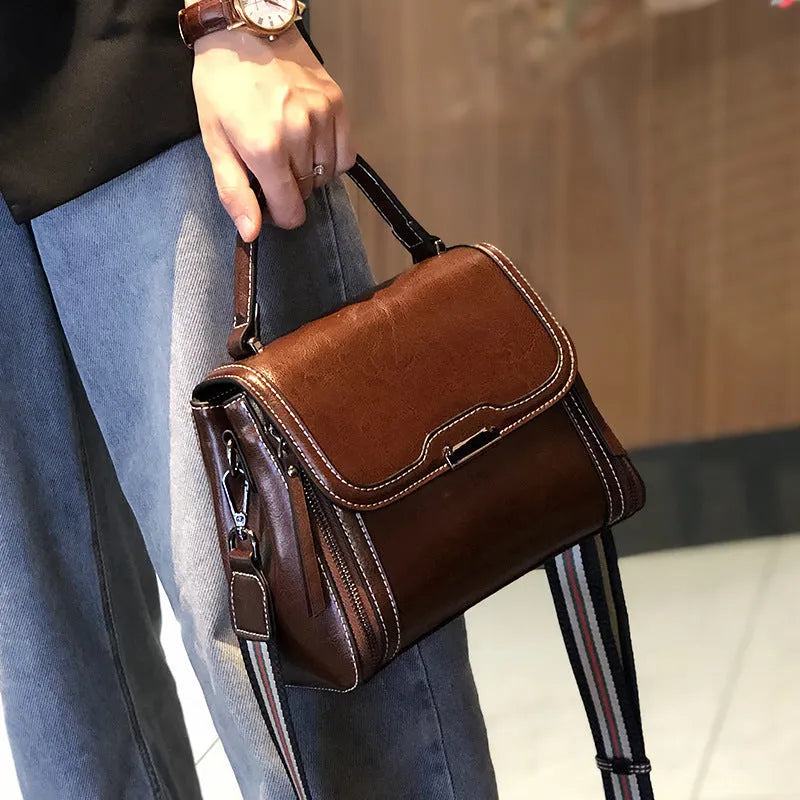 Women's brown genuine oil wax leather messenger bag with double strap and external pocket.