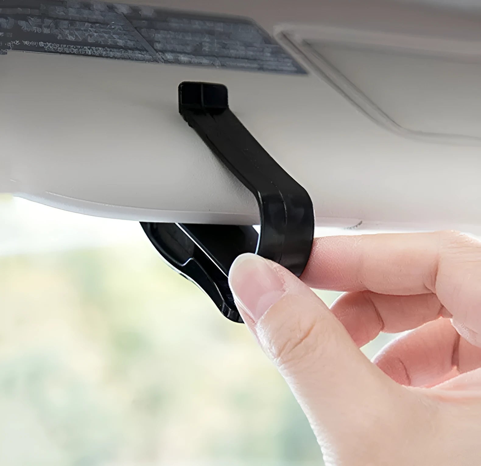 Black plastic clip for car sun visor holding a pair of glasses and a ticket.