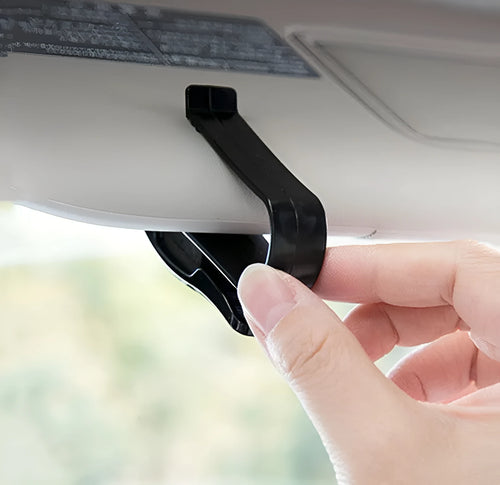 Black plastic clip for car sun visor holding a pair of glasses and a ticket.
