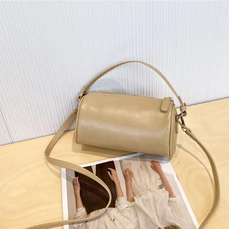 Soft vegetable-tanned leather crossbody phone bag in cylindrical shape with adjustable strap.