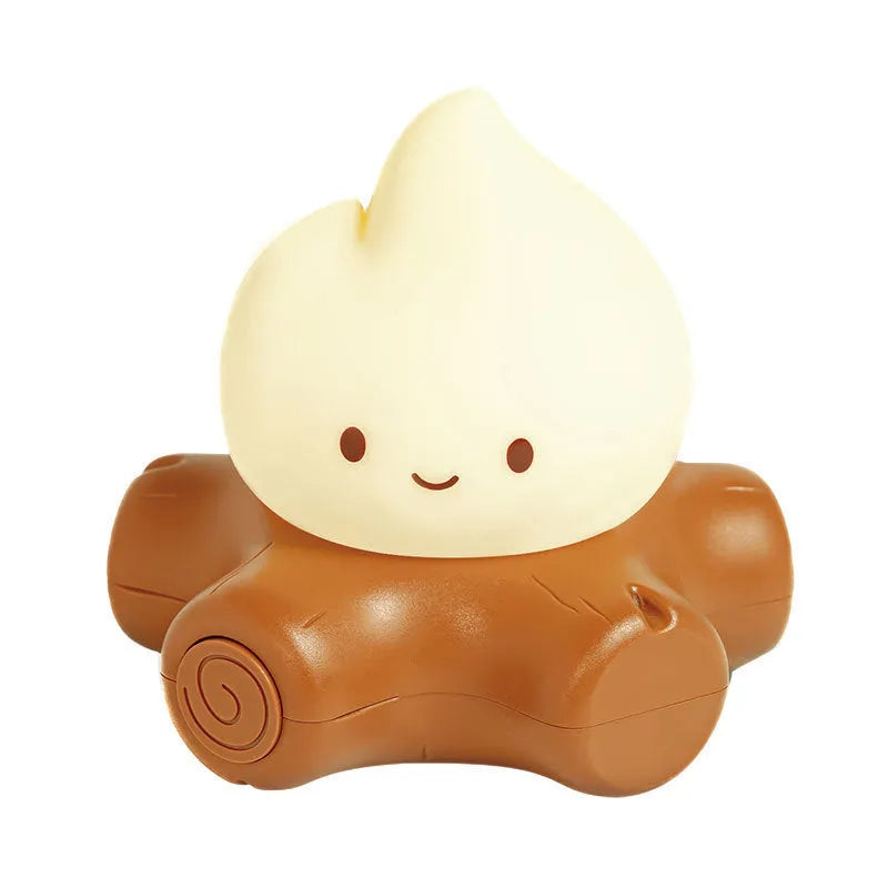 Silicone cartoon fire pile night light with yellow LED illumination on a bedside table.