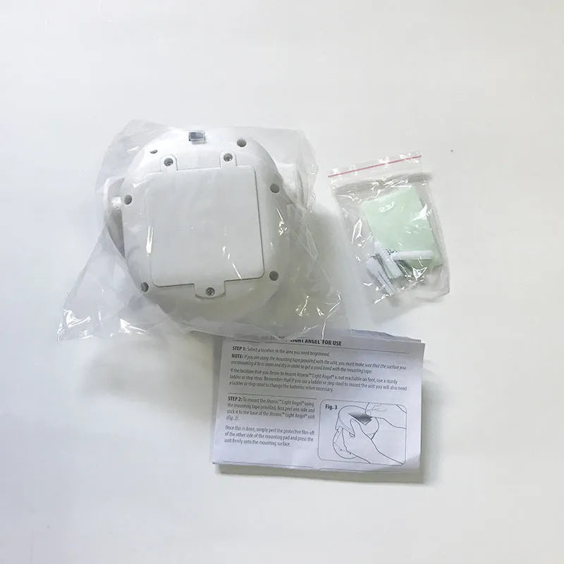 White Atomic Angel induction table lamp with compact ABS plastic body on a table.