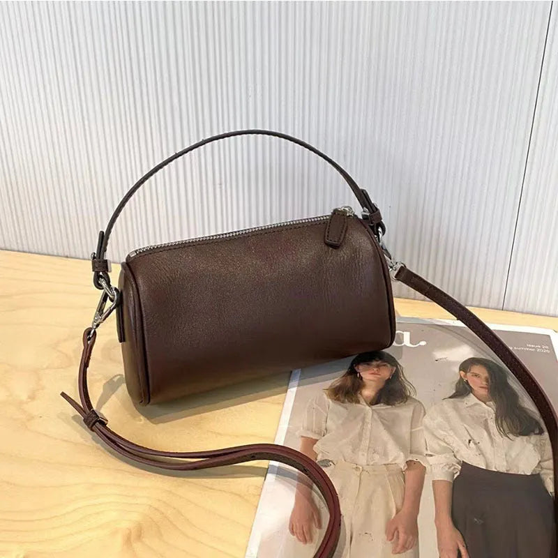 Soft vegetable-tanned leather crossbody phone bag in cylindrical shape with adjustable strap.