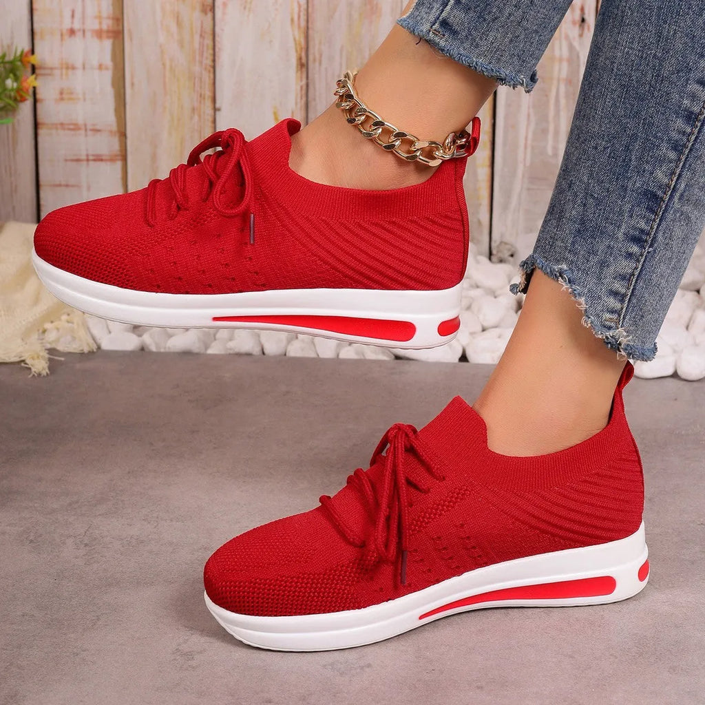 Women's low-top red fly-knit sneakers with round toe and lace-up front on a white background.
