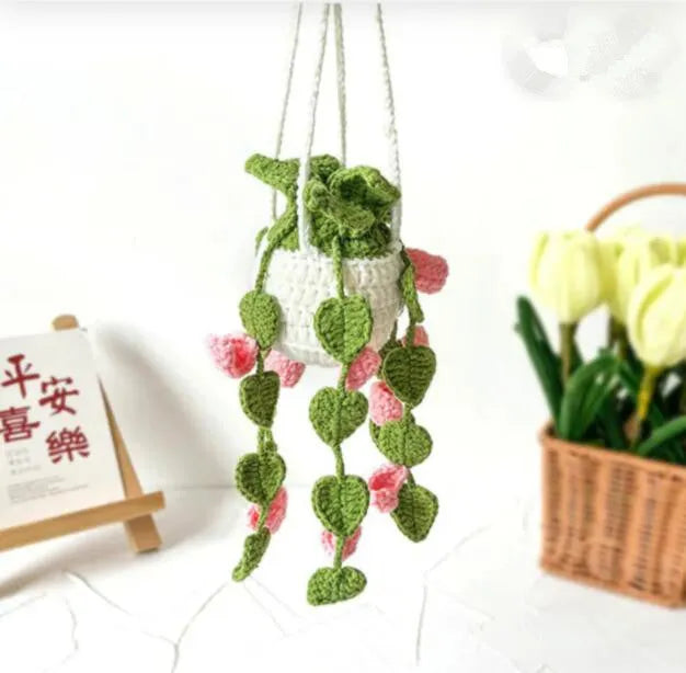 Green and white knitted wool car plant decoration with white hanging rope.