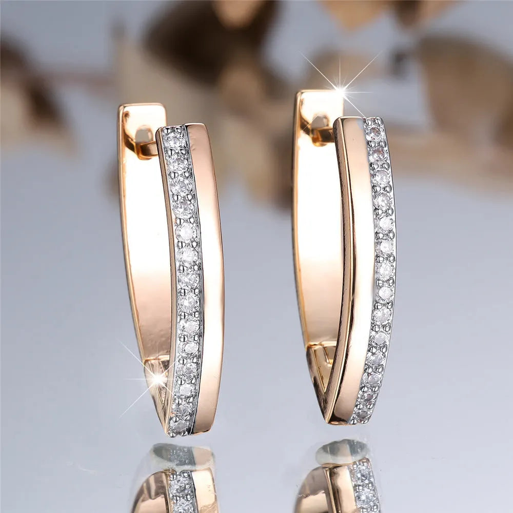 Women's geometric drop earrings with champagne gold electroplating and white diamond accents, showing V-shaped design and clip-on back.