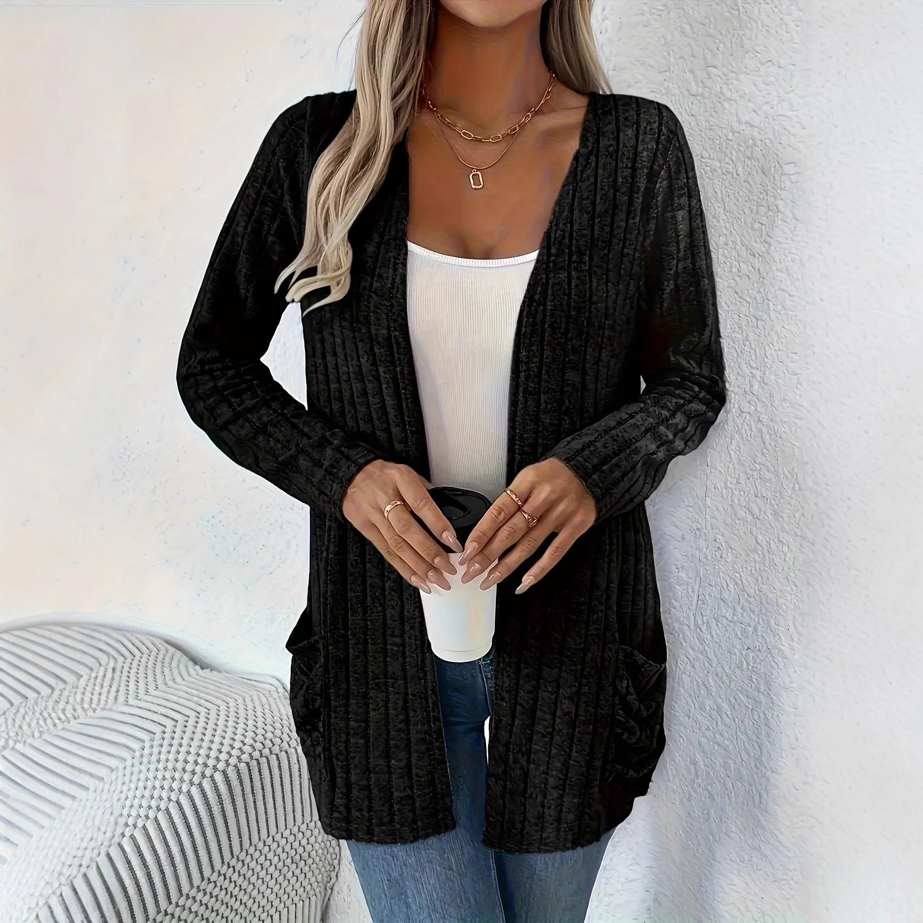 A grey loose fit long sleeve cardigan with pockets hanging on a hanger.