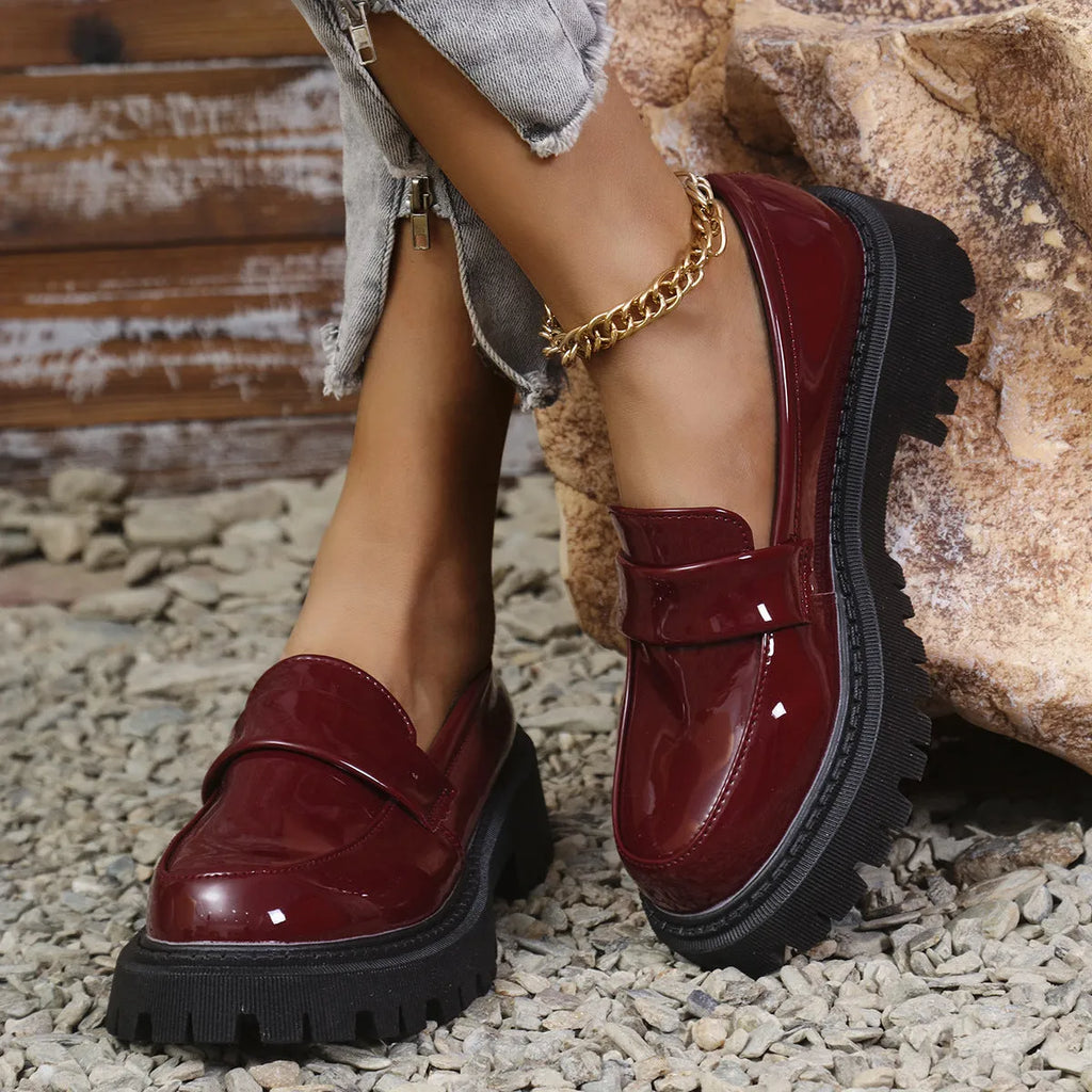 Women's black slip-on loafers with a chunky platform heel and rubber sole, shown from the side.