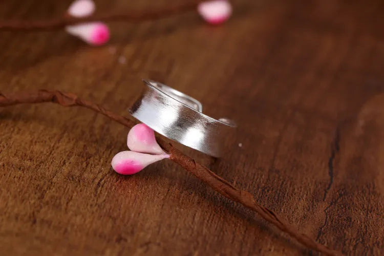 Adjustable open ring in frosted sterling silver with a geometric shape on a grey background.