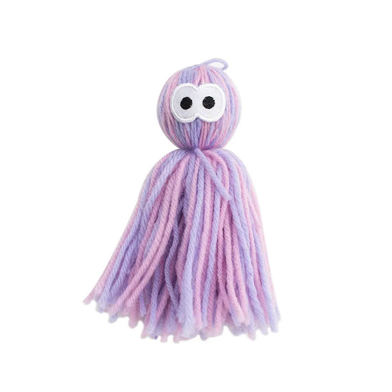Blue grey wool cat toy with teaser stick hanging from furniture