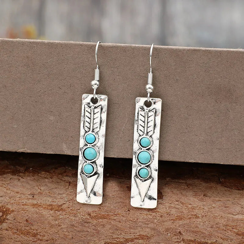Silver geometric drop earrings with turquoise inlay details on white background