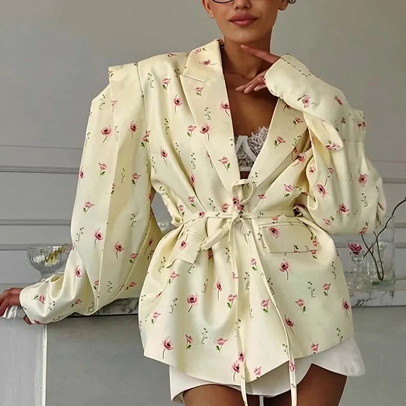 Women's white blazer with a lace-up fastening detail at the waist, shown on a hanger.