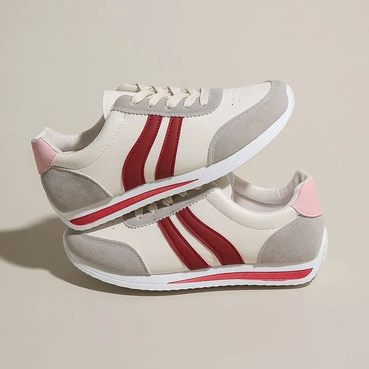 Red and blue lace-up running sneakers with soft rubber sole and mesh upper on white background