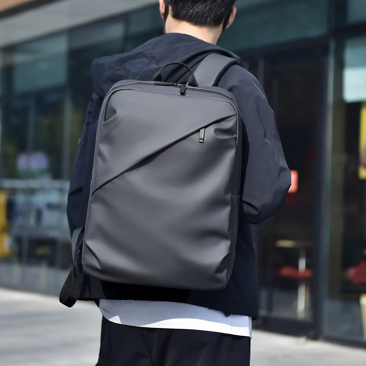 Waterproof PU leather backpack in black, blue or grey showing simple design and sewing thread detailing