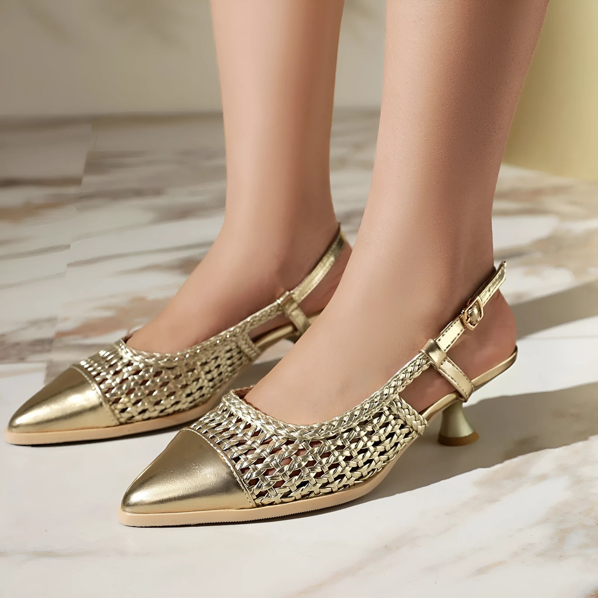 Gold women's sandals with a cat heel and ankle buckle on a white background.