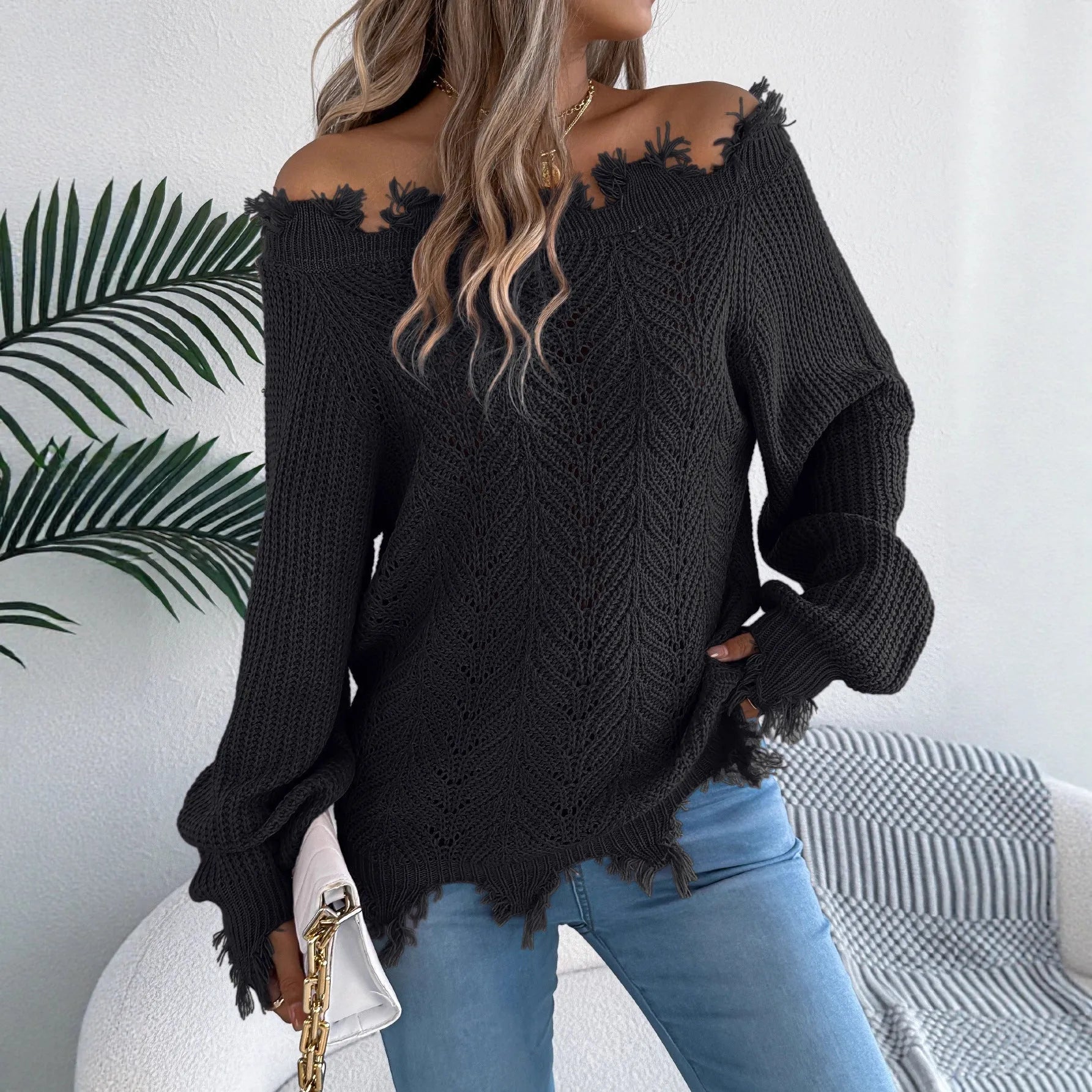 A woman wearing a white hollow-out cut off-the-shoulder pullover sweater in a street fashion style.