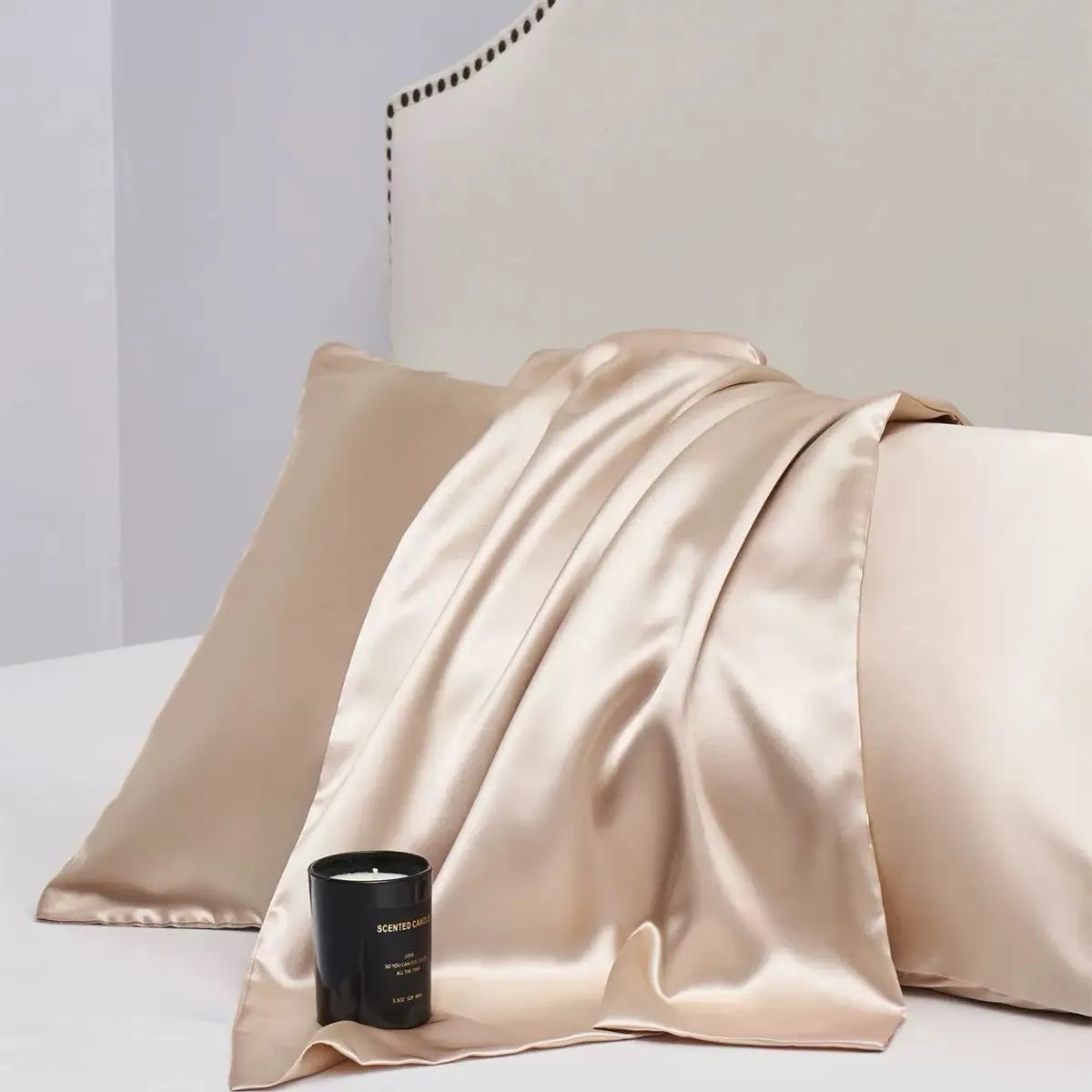 Pair of solid colour satin pillowcases in polyester fabric on a bed.