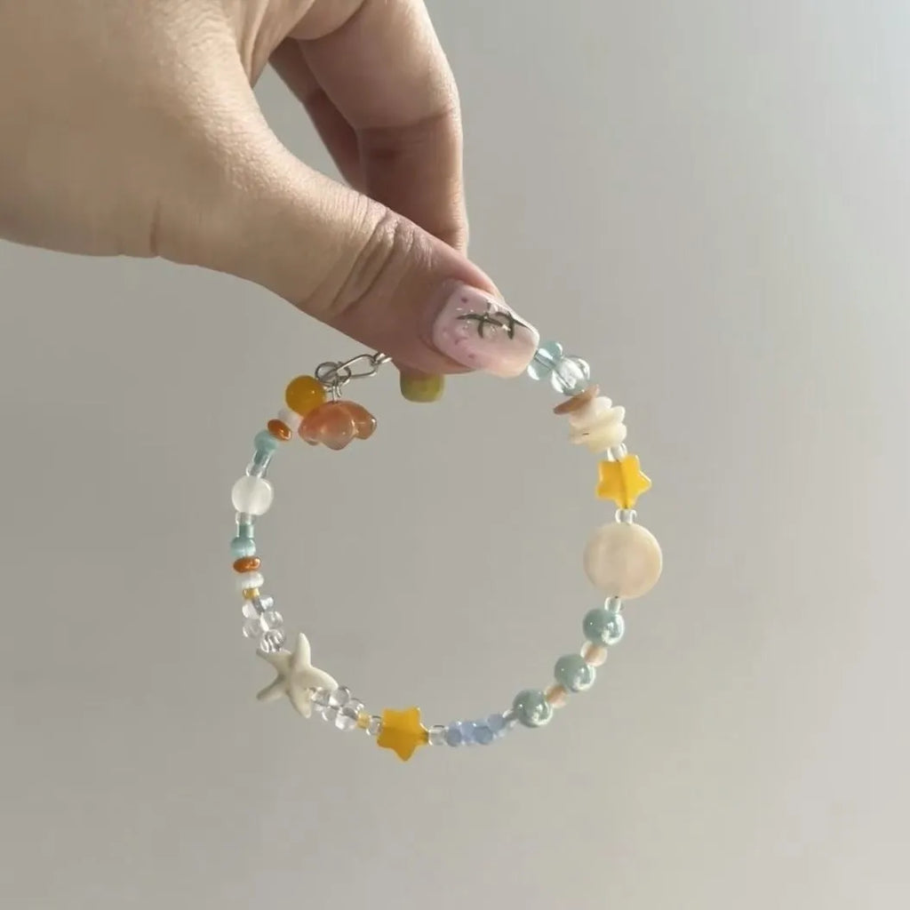Orange summer bracelet with diamond-shaped alloy charm and round elements on mixed-material band