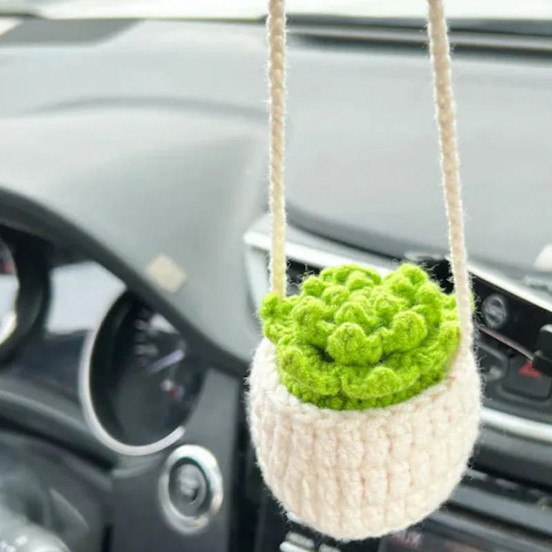 Green and white knitted wool car plant decoration with white hanging rope.