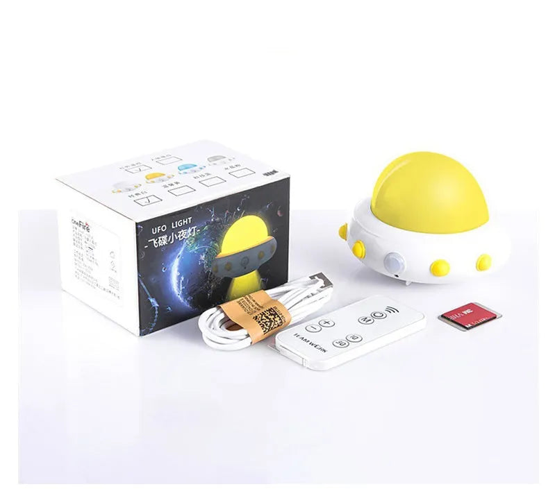 A small blue UFO-shaped bedside night light with a remote control on a wooden table.