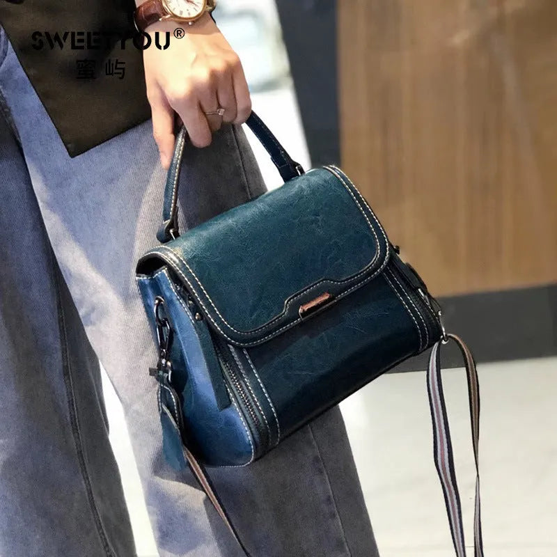 Women's brown genuine oil wax leather messenger bag with double strap and external pocket.