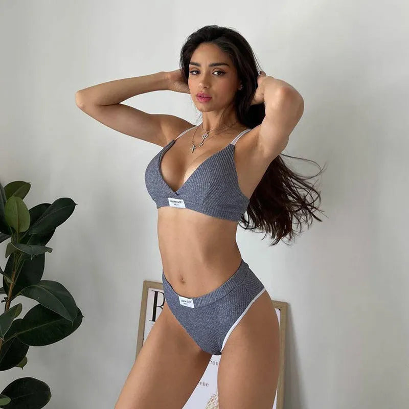 Women's black bikini set with contrast binding and embroidered lettering on a sleeveless top and shorts.