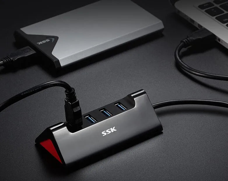 Black USB expansion dock with 4 ports on a desk next to a laptop.