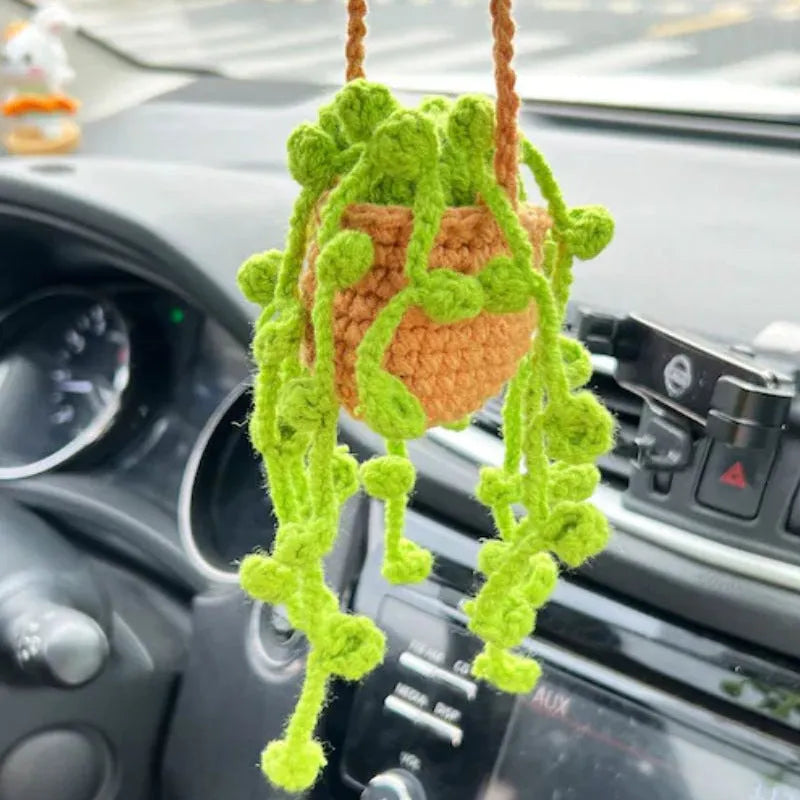 Green and white knitted wool car plant decoration with white hanging rope.